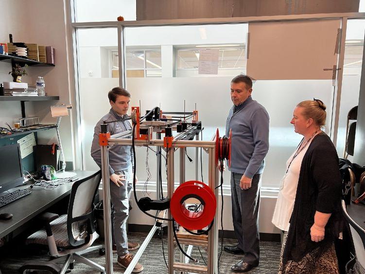 Three people view technological prototype